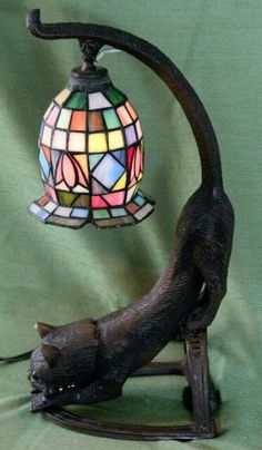 a lamp with a cat on it and a stained glass ball hanging from the base