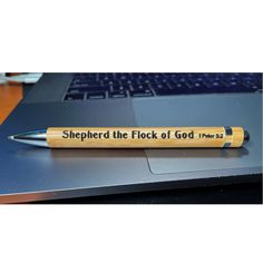 a pen that is sitting on top of a laptop keyboard, which says shepherd the flock of god