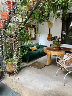 an outdoor living area with plants and potted plants on the walls, couches and tables