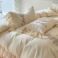 an unmade bed with ruffled sheets and pillows on top of it in a white room