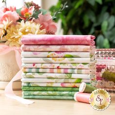 a stack of folded fabric sitting on top of a table next to flowers and other items