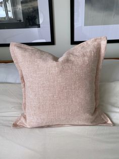 two framed pictures hang on the wall above a bed with white sheets and pink pillows