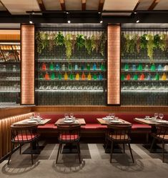 an empty restaurant with red booths and wooden tables in front of colorful glass shelves on the wall