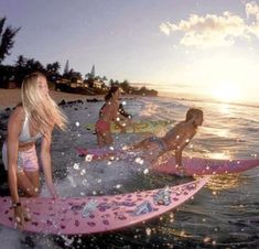 three girls are riding surfboards in the water at sunset or sunrise on the beach