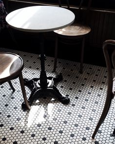 three wooden chairs sitting next to each other on top of a floor covered in black and white tiles