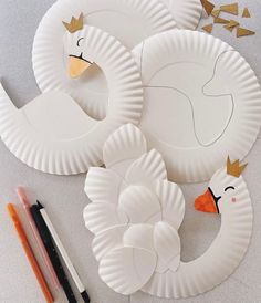 some paper plates with ducks on them next to markers and pencils in front of them