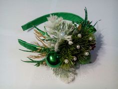 a green and white flower arrangement with pearls, pineconis and other greenery