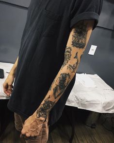 a man with a tattoo on his arm standing in front of a table and chair