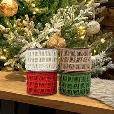 two rolls of yarn sitting on top of a wooden table next to a christmas tree