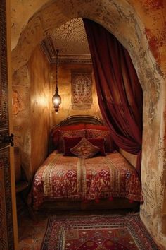 a bed sitting in the middle of a bedroom under a red canopy over it's headboard