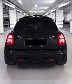 the back end of a black car in a parking garage