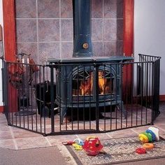 a fire place sitting in the middle of a living room next to a baby gate