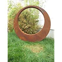 a circular mirror sitting on top of a lush green field