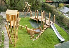 a wooden playground with slide and water play area in the back yard, surrounded by green grass