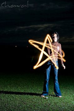 a man standing in the grass holding a star shaped light wand with it's hands