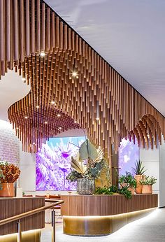 the interior of a restaurant with wood slats hanging from the ceiling and potted plants on the counter