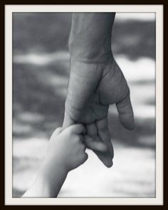 a black and white photo of a person holding the hand of a child's hand