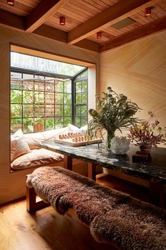 a living room filled with furniture and a large window next to a wooden table topped with a potted plant