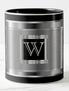 a black and silver coffee mug with the letter w on it's front side