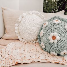 two crocheted pillows on a bed next to a blanket and pillow case with flowers