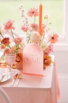 the table is set with pink flowers and candles