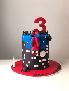 a spiderman birthday cake with the number three on it's top and decorations