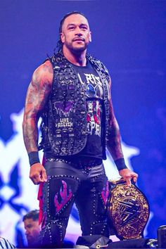 a man in black wrestling gear standing on top of a stage with his hands behind his back