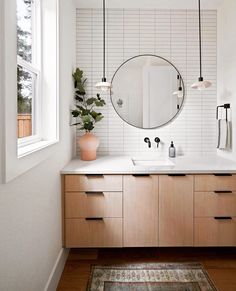 a white bathroom with wooden cabinets and a round mirror