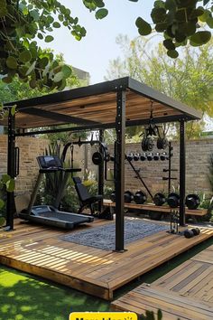 an outdoor gym with exercise equipment in the middle of a wooden deck and green grass