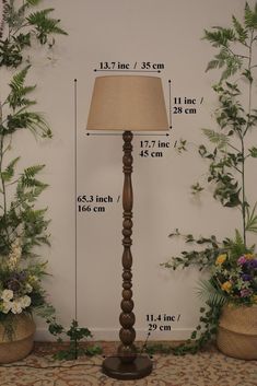 a tall wooden floor lamp next to potted plants