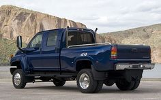 a blue pick up truck parked in front of a mountain