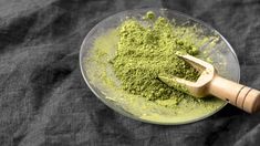 a bowl filled with green powder next to a wooden handled hammer on a black cloth