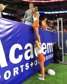 two people are standing on a sign at a sporting event