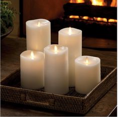 six white candles are sitting in front of a fireplace