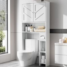 a white toilet sitting in a bathroom next to a sink and cabinet with towels on it