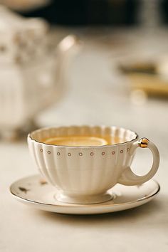 a white cup and saucer sitting on top of a table