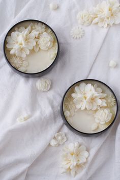 three bowls filled with white flowers on top of a bed