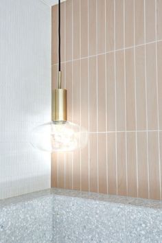 a light that is hanging from the ceiling in a room with tile on the walls