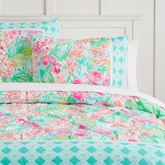 a bed covered in green and pink floral comforter sets with matching pillow shampoos