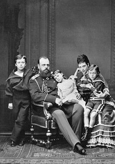 an old black and white photo of a family sitting on a chair in front of a wall