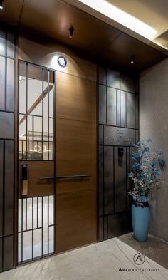 a vase with blue flowers sitting in front of a wooden door that has glass panels on it