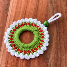 a green and white crocheted wreath on a wooden table with a string attached to it