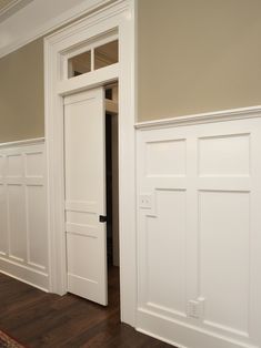 an empty room with white paneling on the walls and wood floors, along with a rug