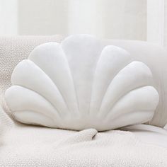 a white shell shaped pillow sitting on top of a couch