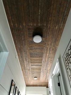 a hallway with white walls and wooden ceiling