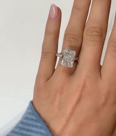 a woman's hand with an engagement ring on her left and the middle finger