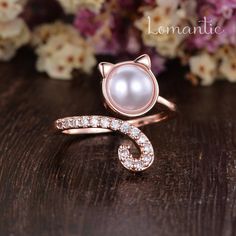 an image of a cat ring with pearls on it's side and flowers in the background