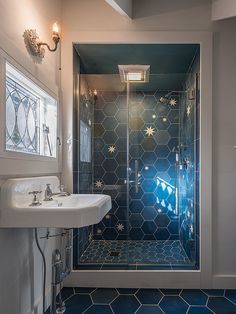 a bathroom with a glass shower door and blue floor tiles on the walls, along with a pedestal sink