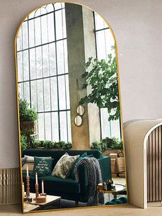 a living room filled with furniture and a large mirror in the middle of it's wall