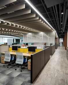 an office cubicle with two people working at desks on the opposite side of the room